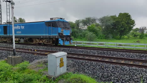powerful blue indian railways locomotive with cargo containers speeding down tracks, dynamic motion and industrial transport.