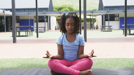 Biracial-girl-meditates-with-eyes-closed-in-a-schoolyard