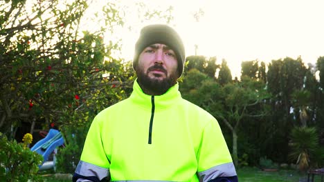 hombre vestido con ropa reflectante amarilla, o uniforme de trabajador público, con un martillo en las manos sonriendo a la cámara