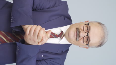 vertical video of old businessman making a trust sign at the camera.