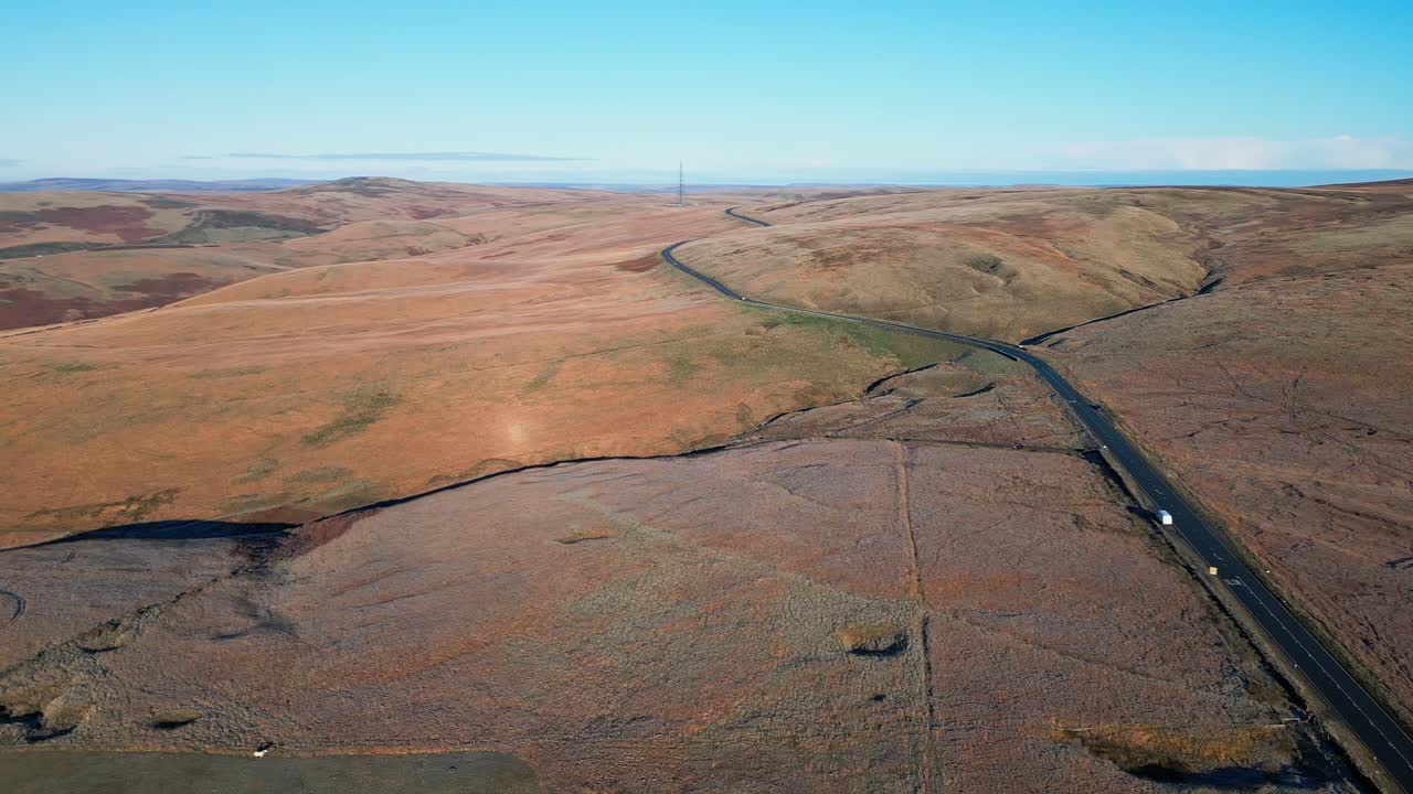 coche distante conduciendo por una estrecha carretera rural en los páramos del reino unido con paisaje barron