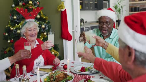 Fröhliche-Gruppe-Verschiedener-älterer-Freunde,-Die-Zur-Weihnachtszeit-Essen-Feiern-Und-Saft-Trinken