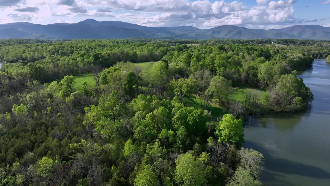 Forest landscape with Mill Creek Lake in America during sunny day. Mountain formation in distance. Rising drone wide shot. Calm nature in spring season.