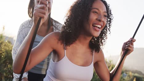 romantic biracial lesbian couple playing on swing and embracing in garden at sundown, slow motion