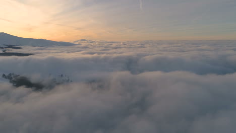 over-a-clouds,-in-front-of-snowy-forrest,-mountain-peaks-and-sunset-colors