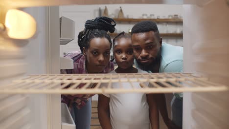 afro-american hungry family looking into empty fridge at home