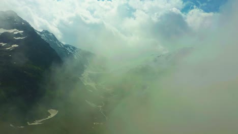 drone fly into clouds in scenic snowy mountains in alps, switzerland