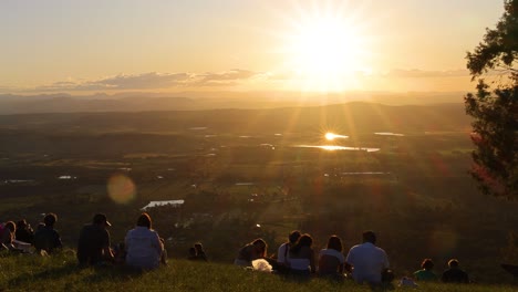 group of people watching sunset over scenic landscape