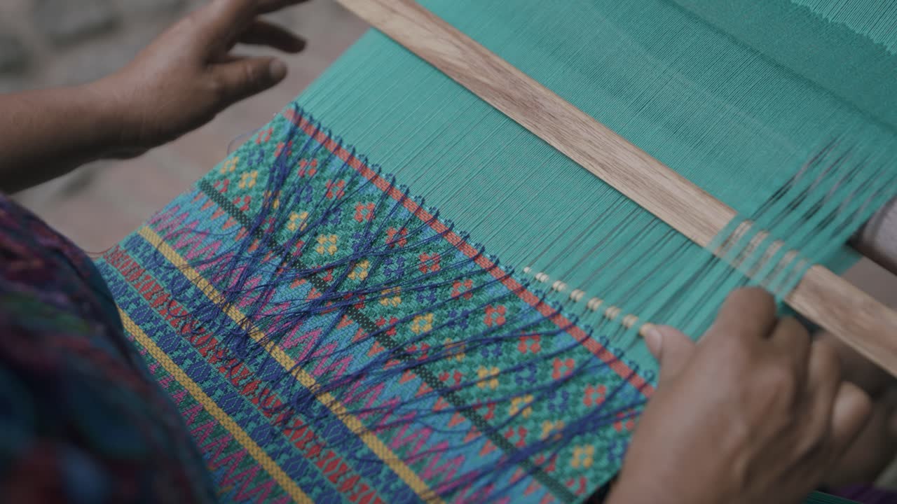 cámara lenta mientras una mujer enhebra una aguja a través de una tela en guatemala