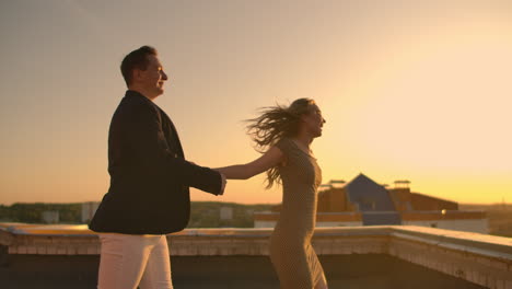 A-man-with-a-woman-running-on-the-roof-holding-hands.-Slow-motion-lovers-on-the-roof.