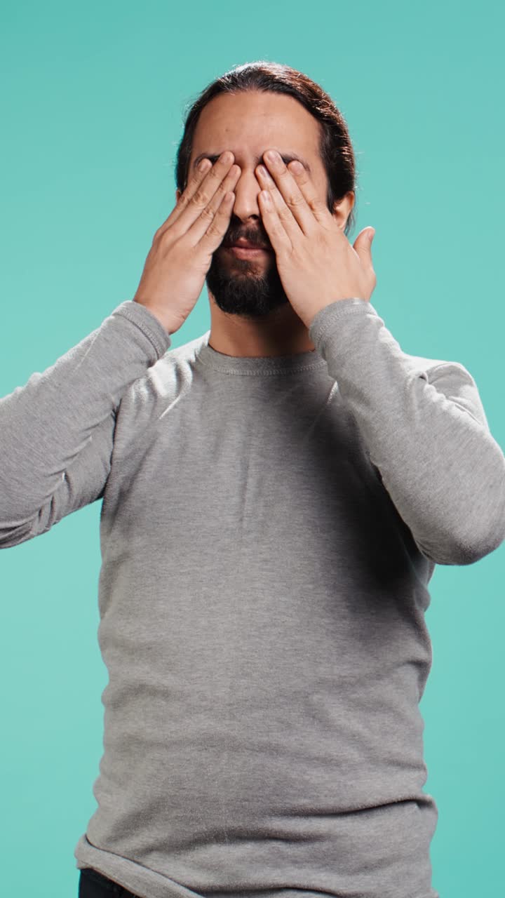 Video verticale: uomo che si copre occhi, orecchie e bocca, imitando le tre scimmie sagge