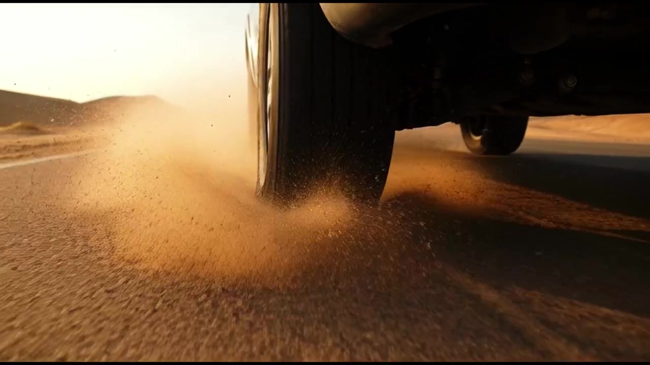 Primo piano di uno pneumatico dell'auto che guida su una strada nel deserto al tramonto