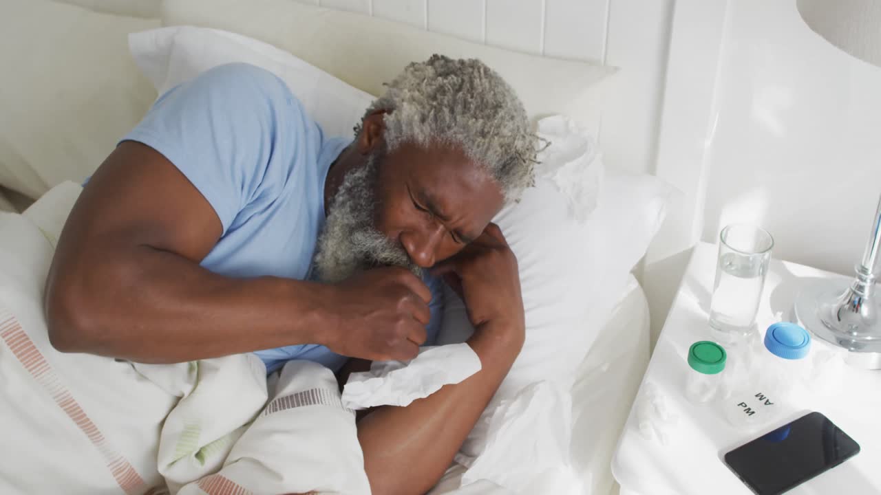Uomo anziano con un fazzoletto che tossisce a letto a casa