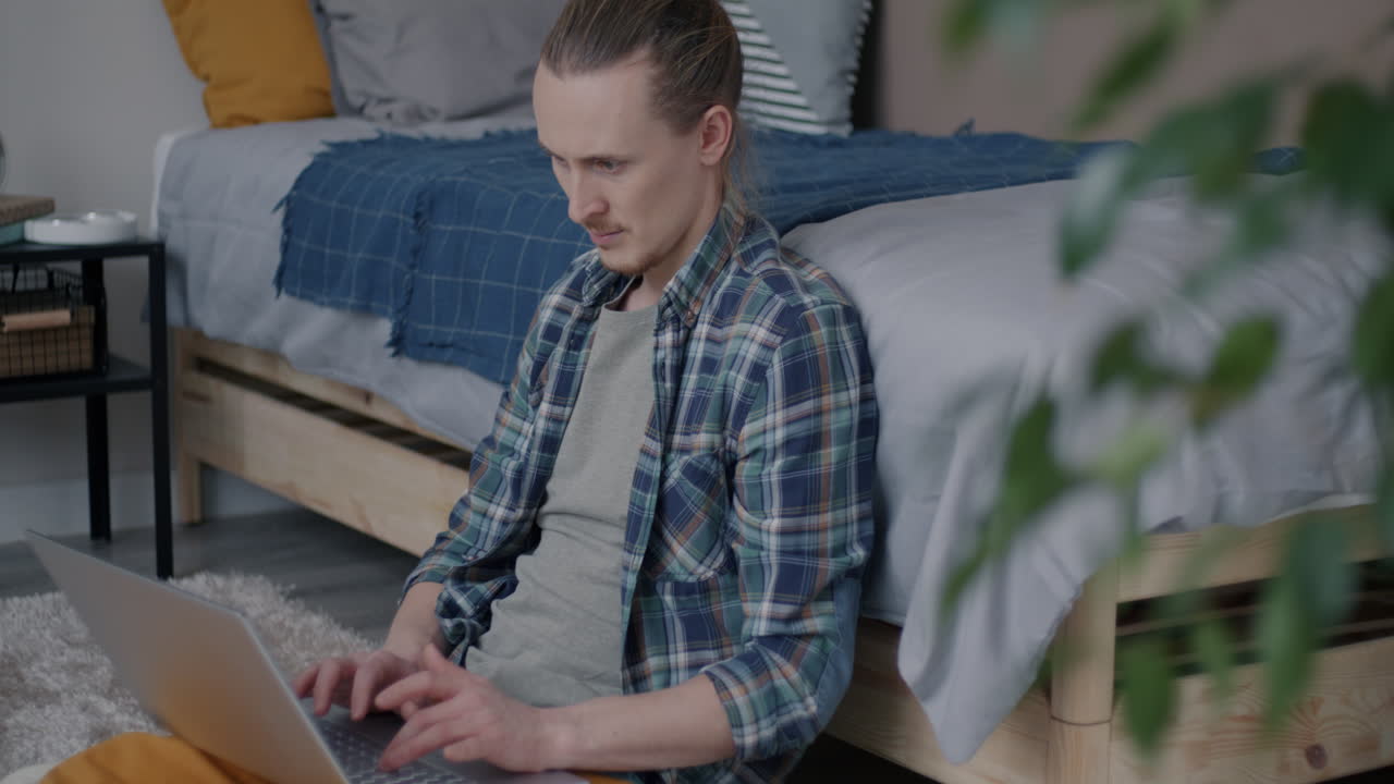 Man working on laptop in bedroom