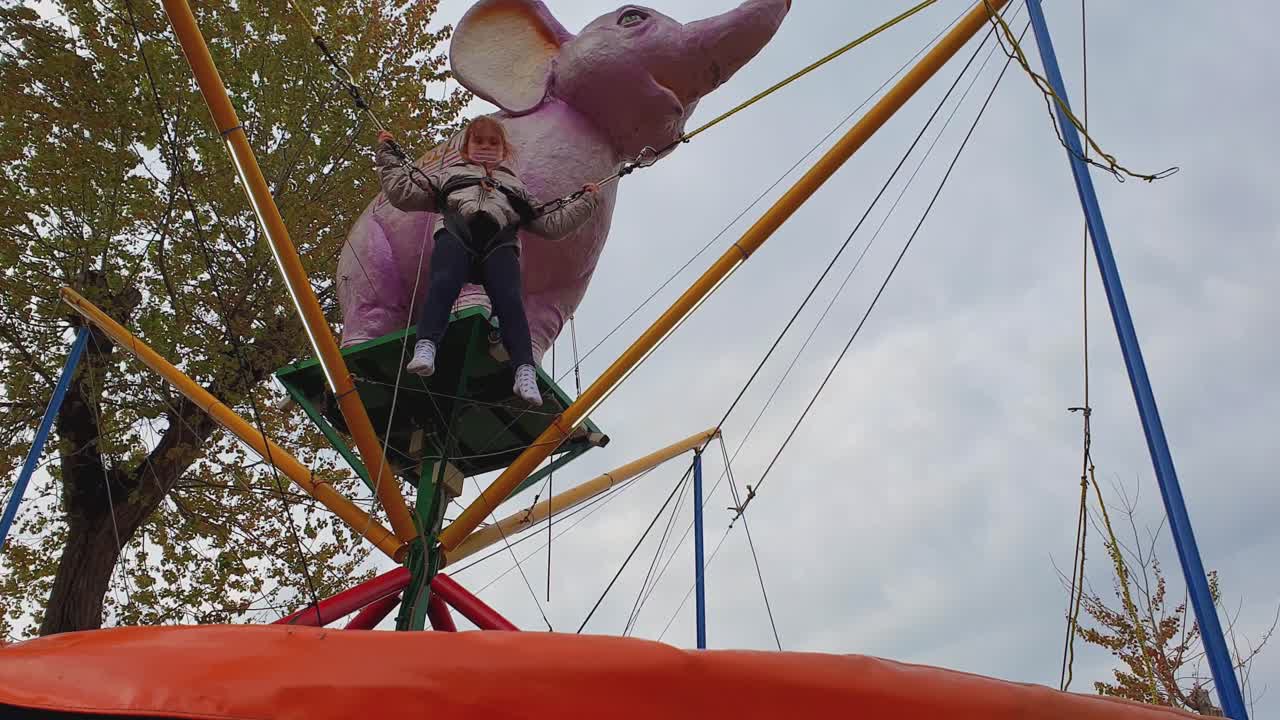 una niña feliz saltando en un trampolín de bungee en un día de invierno