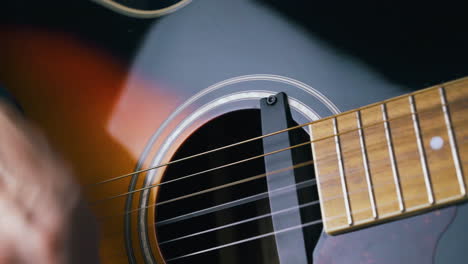 person plays black and brown acoustic guitar with pick