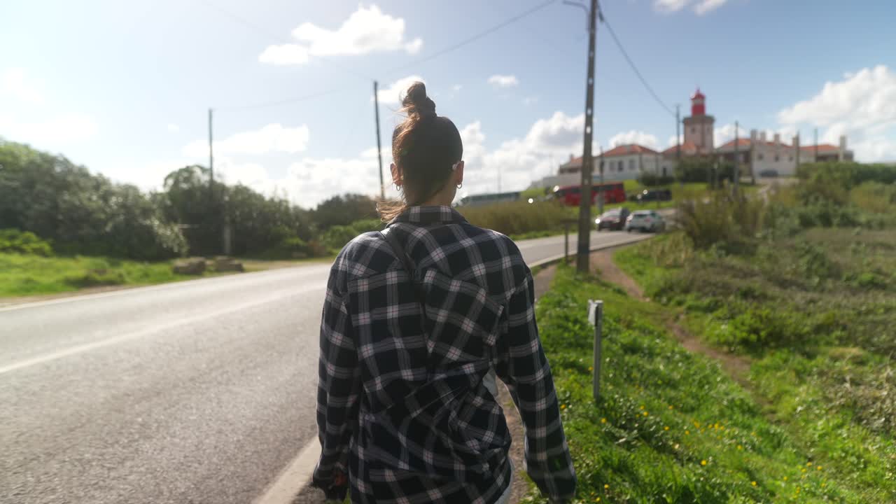 Woman Walking Towards Lighthouse on a Sunny Day
