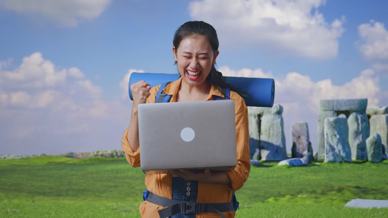Woman Celebrates a Successful Trip with a Laptop at Stonehenge
