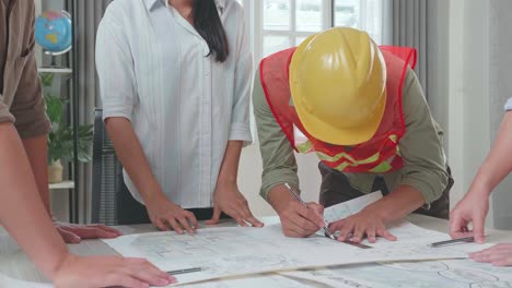three asian engineers with helmets and a man celebrating finish drawing building construction while working at the office