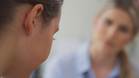 close up of doctor talking to crying teenage female patient suffering with mental health problems