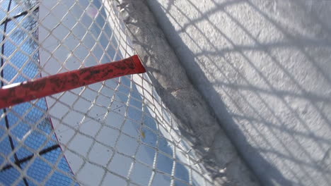 unique view of a puck firing into a hockey net during an outdoor game on an ice pad