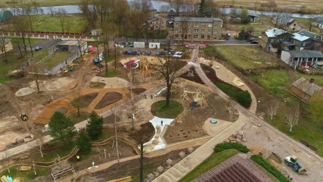 a bulldozer is excavating and relocating soil at a park construction site - aerial drone shot