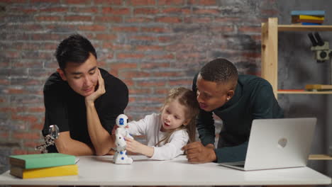 Little-girl-waves-hand-before-robot-sensor-with-teachers