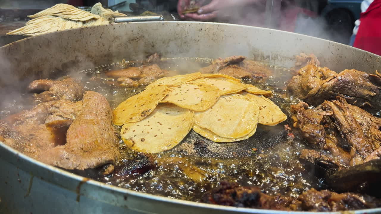 Primo piano di tradizionali tacos messicani da strada con carne di suadero e longaniza in preparazione su una piastra. Autentica esperienza culinaria a CDMX