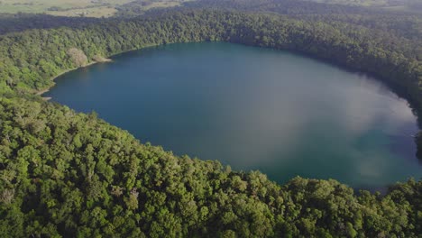 lake eacham surrounded with verdant vegetation in atherton tableland, queensland, australia - aerial drone shot