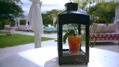 close view of bloody mary cocktail in lantern by pool at resort