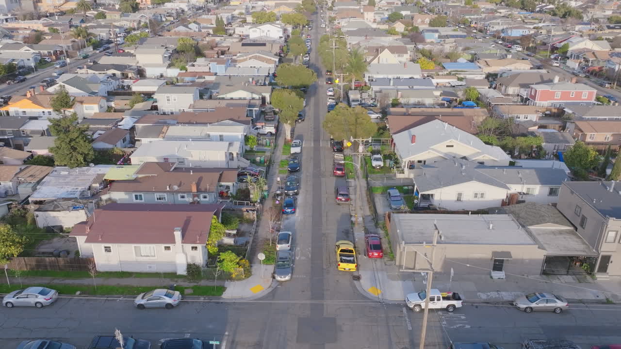 Aerial footage slowly flying down a street in a neighborhood during sunset in Oakland, California.