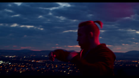 man practicing martial arts at sunset over a city