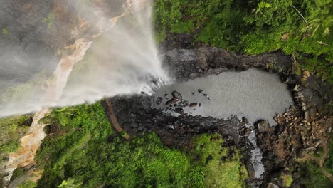 una cortina constante de agua fluye sobre un acantilado escarpado hacia abajo a una piscina de roca natural