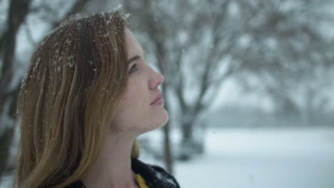 happy woman outside in slow motion winter snow as snowflakes fall in cinematic slow motion