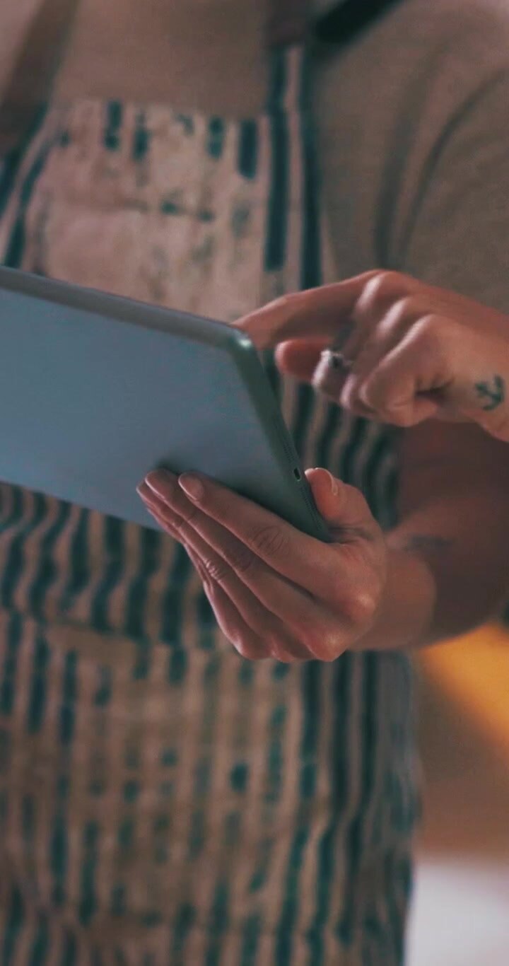 Person Wearing Apron Using a Digital Tablet