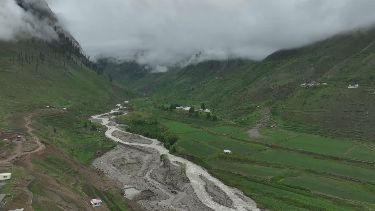 Follow shot of drone over the lake and green valley in Naran Batakundi in northern region of Pakistan with low clouds