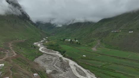 follow shot of drone over the lake and green valley in naran batakundi in northern region of pakistan with low clouds