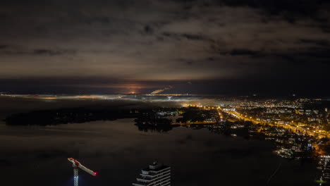 night cityscape with construction crane and fog