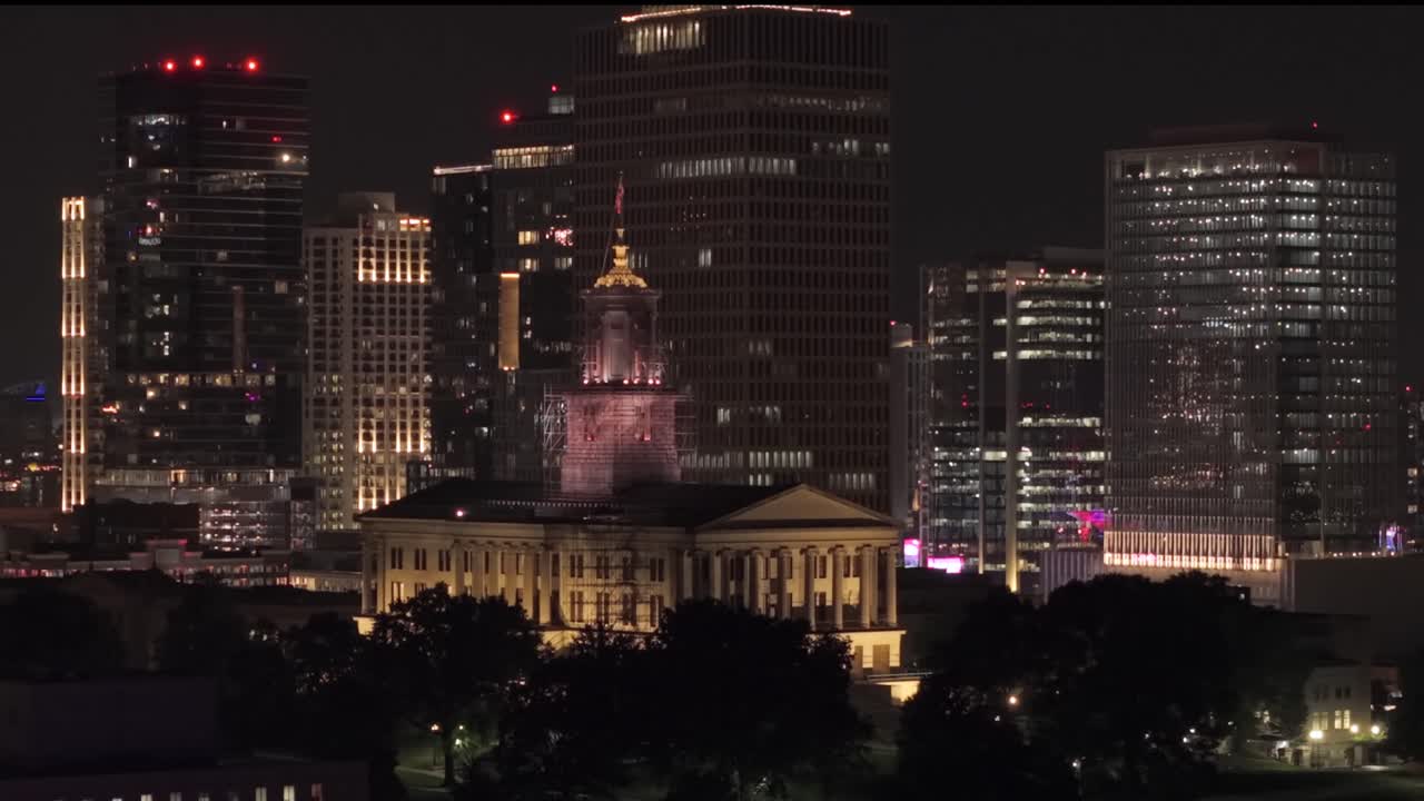 A nighttime aerial view showing the lit State Capitol and towering skyscrapers in Downtown Nashville, Tennessee