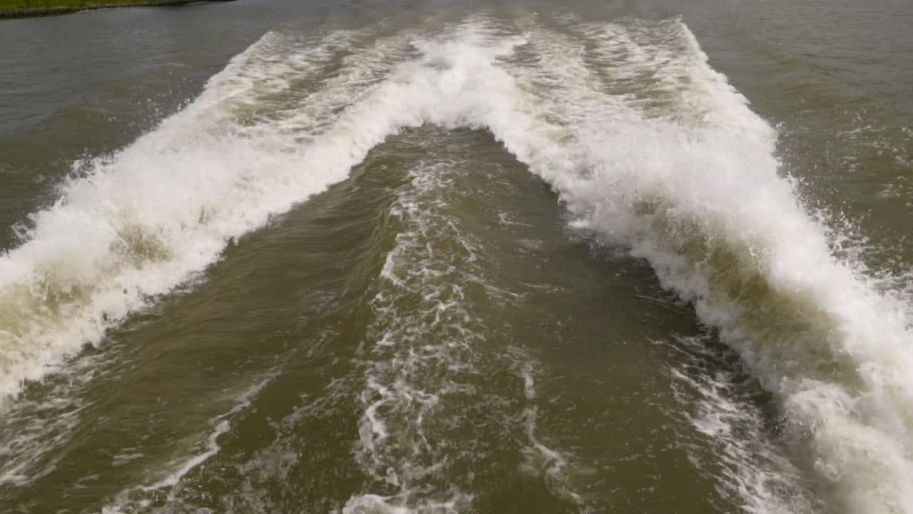 A speed boat and its engine propellers churn the water into high waves