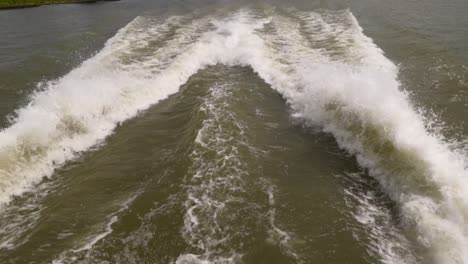 a speed boat and its engine propellers churn the water into high waves