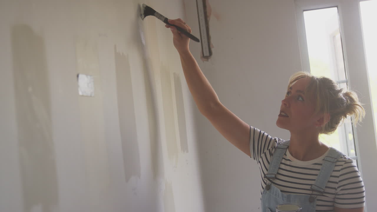 mujer decorando una habitación en la casa probador de pintura pintando tiras de color en la pared