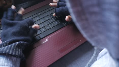 persona escribiendo en una computadora portátil con guantes