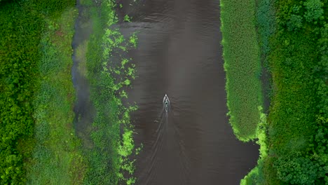 boat on beautiful amazon river traveling through lush rainforest jungle - aerial