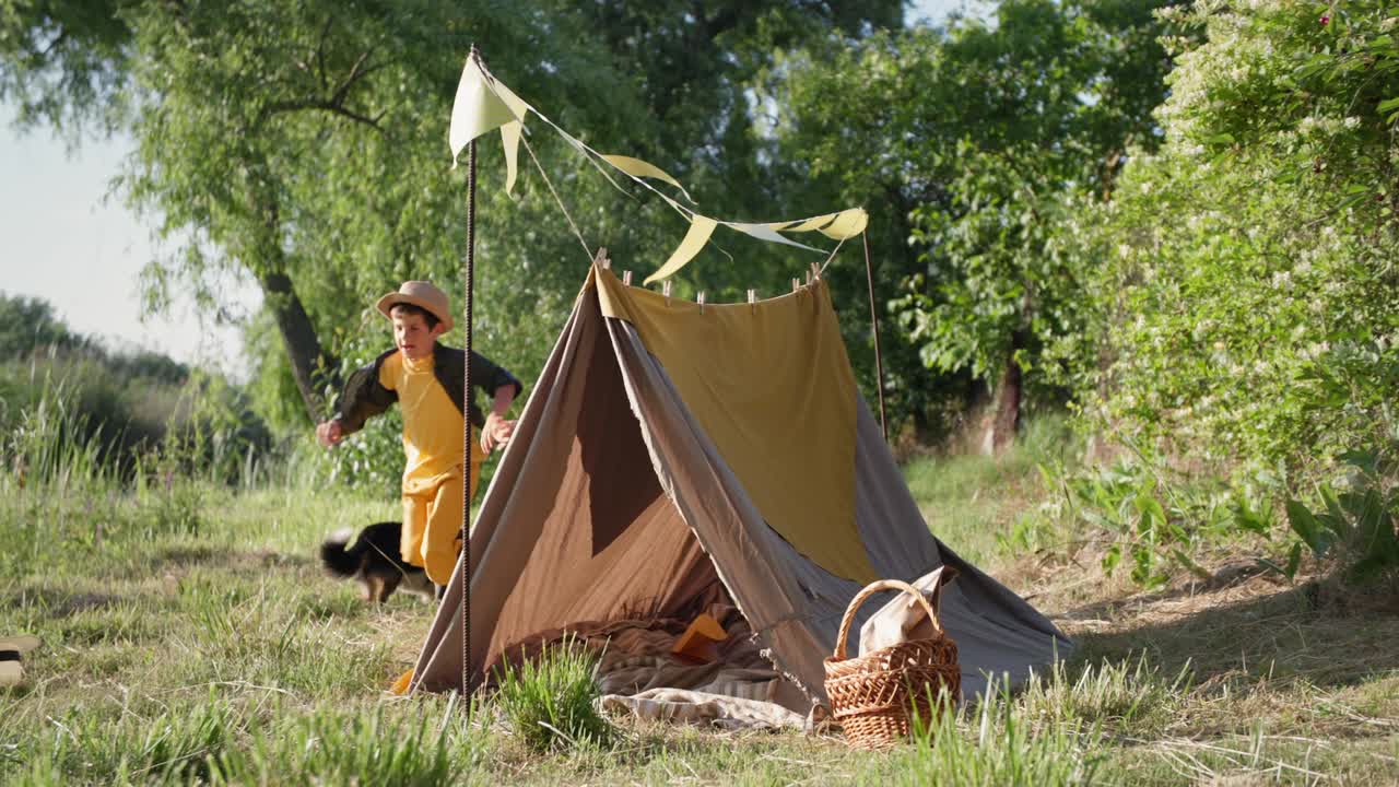 아이들을 위한 활발한 게임, 행복한 형제들은 도시 밖의 여름 휴가 동안 푸른 잔디에서 텐트를 돌아다니며 재미를 느끼고 있습니다.