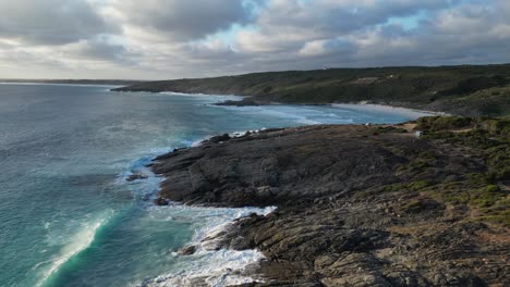 drone flying low over rocky bremer bay in open blue ocean, waves crashing into rocks, australia