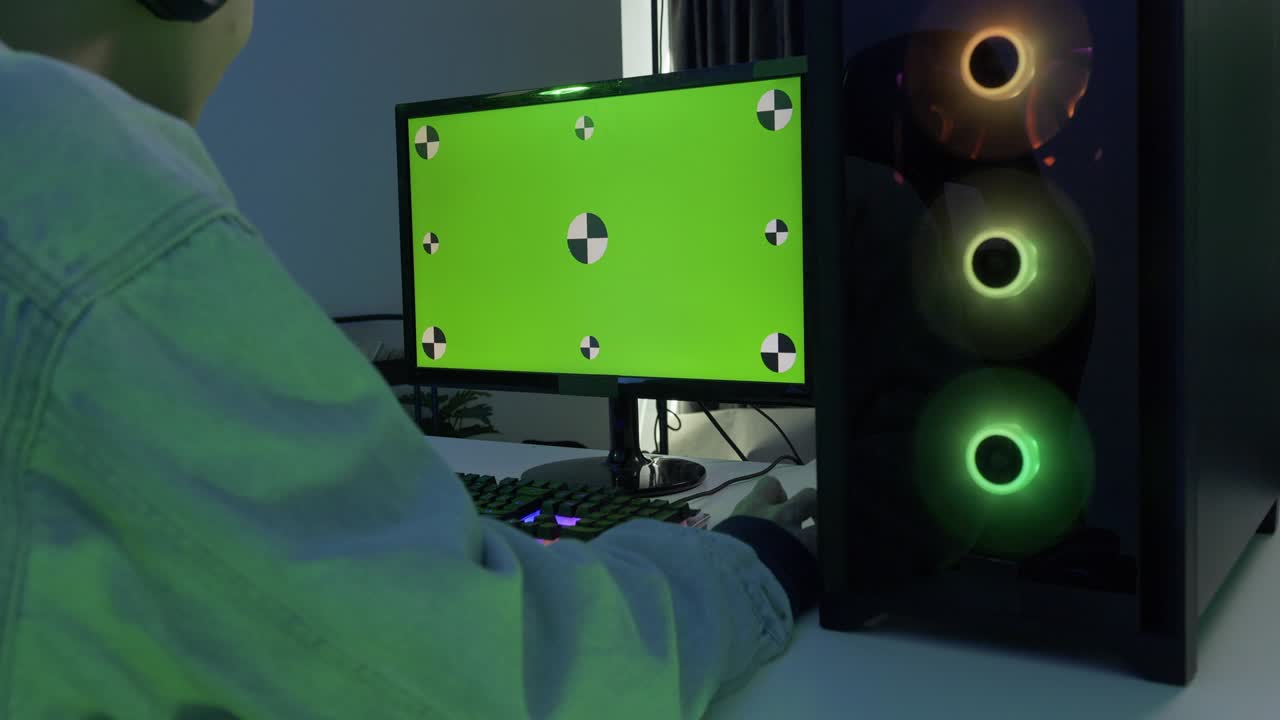 남성 게이머가 집에서 게임을 하고 있습니다. 모니터 내부의 녹색 화면 배경에 초점을 맞추십시오.