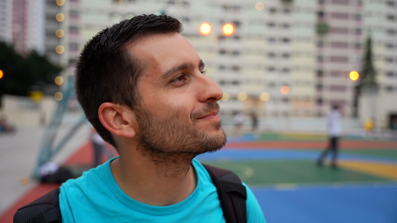 hombre sonriendo a la cámara en la cancha de baloncesto de choi hung estate en hong kong, un entorno colorido y vibrante