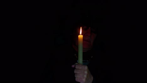 Frightening-creepy-senior-man-with-Halloween-witcher-makeup-looking-at-candle,-conjure,-hex,-wiz