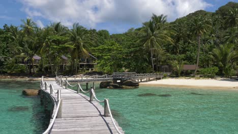 wooden bridge leading onto a tropical white sand beach island